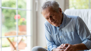 Photo of a mature man experiencing knee pain from osteoarthritis.